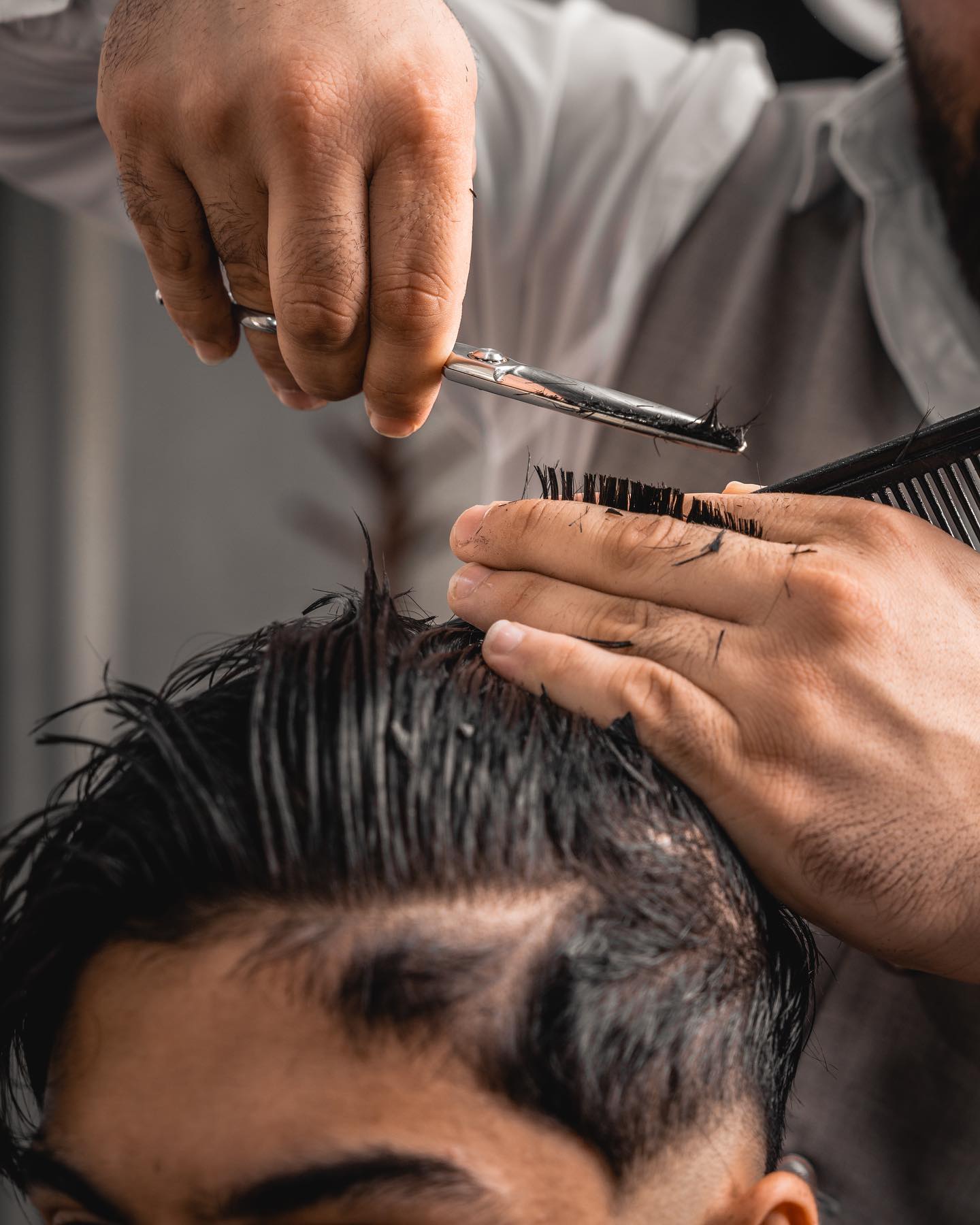 Close-up of scissors and comb cutting hair at Scissors and Razors
